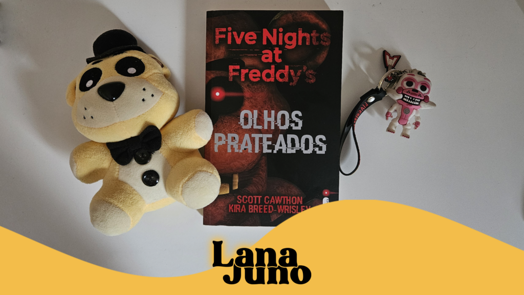 Foto do livro "Five Nights at Freddy's: Olhos Prateados" cercado de dois itens da série de jogos "Five Nights at Freddy's". À esquerda, uma pelúcia do personagem Golden Freddy; à direita, um chaveiro de personagem Funtime Foxy, acompanhado de uma guitarra do personagem Bonnie e as letras "Five Nights at Freddy's". O chaveiro do Funtime Foxy está sem as duas orelhas.